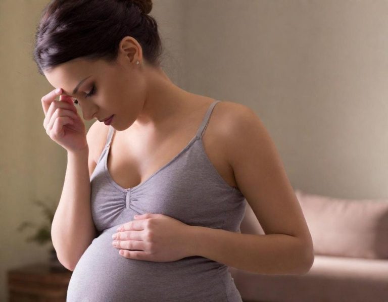 Schwangere-Frau-wirkt-nachdenklich Schwangere Frau berührt ihren Bauch und wirkt emotional belastet